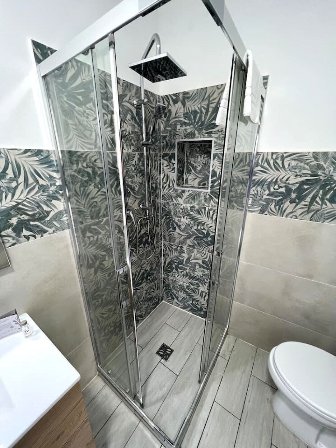 Eine begehbare Dusche mit Duschkopf, kleinem Spiegel und Fliesenboden.