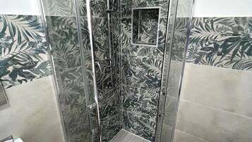Eine begehbare Dusche mit Duschkopf, kleinem Spiegel und Fliesenboden.