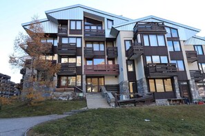 Stylish residential building with modern design, featuring balconies and a grassy entrance area.