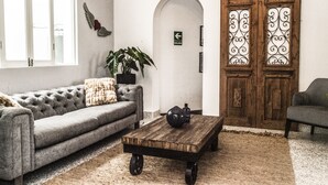 A living room with a grey sofa, a wooden coffee table, a potted plant, and a wooden door with decorative glass panels.