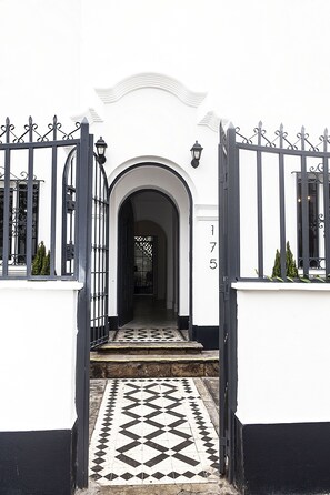 A white building with a black gate and a black and white patterned floor. - WasiPai Boutique Hotel (Lima)