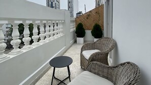 A balcony with wicker furniture, a small round table, and potted plants.