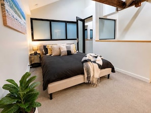 A bedroom with a bed, bedside tables, a lamp, a plant, and a painting on the wall. - Devonport Loft Apartment: A/C Great Location! (Devonport)