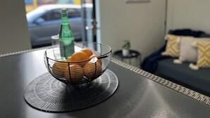 A room with a dining table featuring a wire fruit basket and a green bottle. - Devonport Loft Apartment: A/C Great Location! (Devonport)