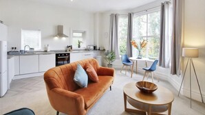 A modern kitchen with white cabinets, a built-in oven, and a window with curtains.