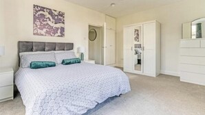 Un dormitorio con cama, armario y espejo.