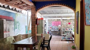 Een eethoek met een bakstenen muur, een muurschildering, een betegelde vloer en een tafel met stoelen.