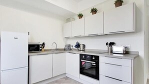 A modern kitchen with white cabinetry, a built-in oven, a microwave, and a toaster. - Stunning 2-bed Apartment in Tunbridge Wells (Royal Tunbridge Wells)