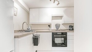 Une cuisine moderne avec des meubles blancs, un four encastré et une machine à café.