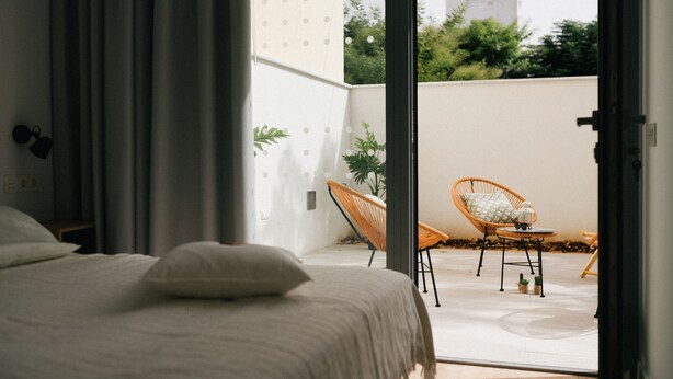 Un dormitorio con una cama, una silla y una pequeña mesa con una planta.