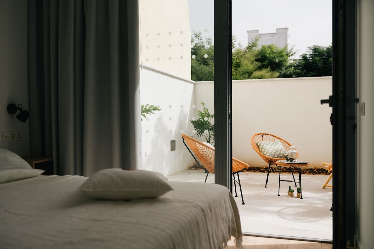 A bedroom with a bed, a chair, and a small table with a plant.
