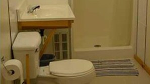A small bathroom with a toilet, sink, and shower. - Family vacation on Black Lake with a private beach! (Hammond)