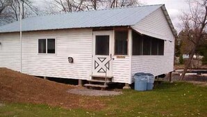A small, single-story white building with a sloped roof, a front door, and a small porch area. - Family vacation on Black Lake with a private beach! (Hammond)
