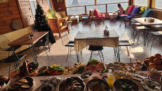 A cozy dining area with wooden walls, a Christmas tree, and a table set with various dishes. - Seedi Yousef Hostel & cafe (Nazareth)