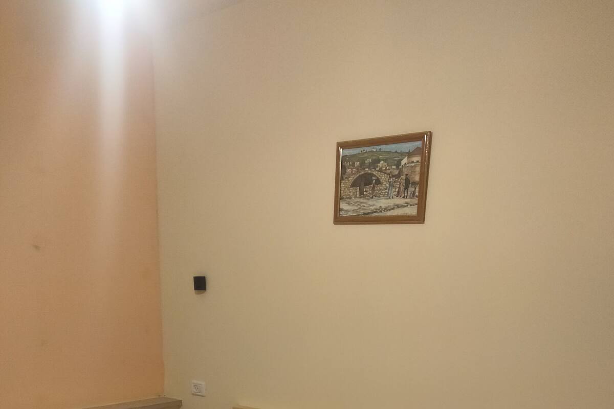 A bedroom with a bed, a nightstand, a lamp, and a framed picture on the wall.