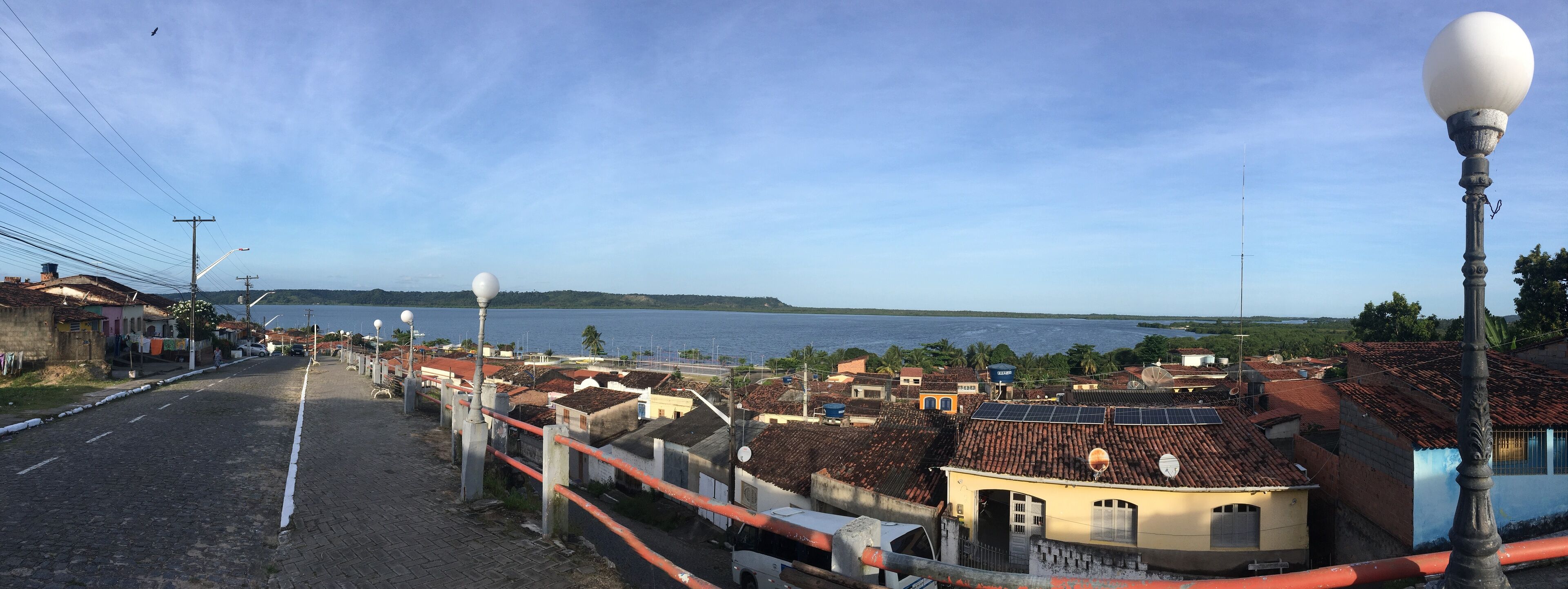 A coastal street with buildings, a clear sky, and a view of the sea.