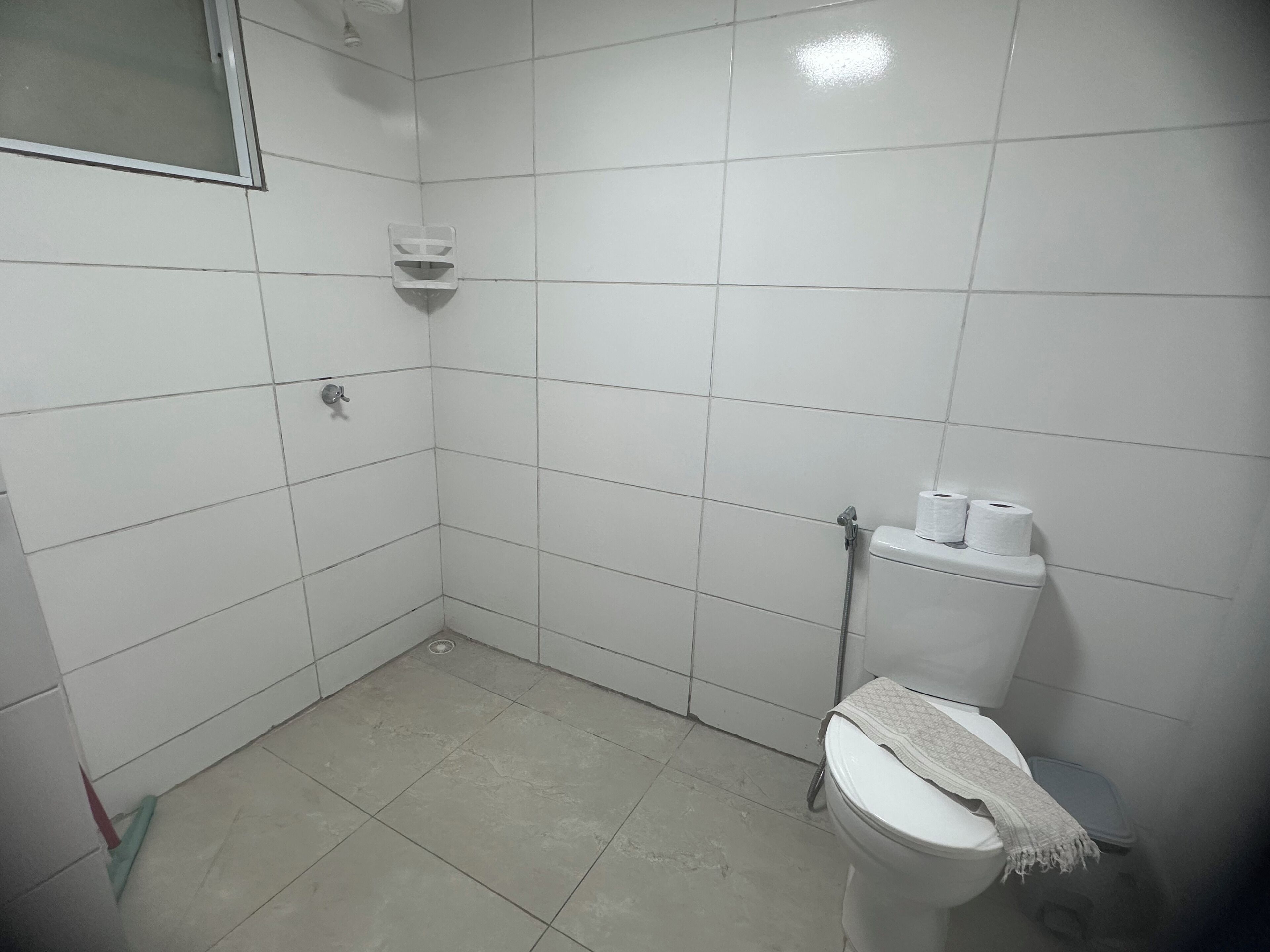 Un baño pequeño con azulejos, un inodoro, una ducha y un secamanos.