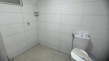 Un baño pequeño con azulejos, un inodoro, una ducha y un secamanos.