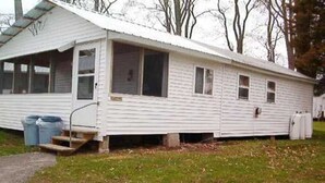 Ein Bungalow mit Veranda, einem kleinen Vorgarten und einem Auffahrt mit Kies.