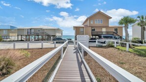 A wooden boardwalk leading to a beachfront property with multiple buildings, a parking area, and a view of the ocean. - Sunset Bungalow on 30A - AWESOME SPOT ON30A- 4BR/2BA, Fabulous Views of the Gulf (Santa Rosa Beach)