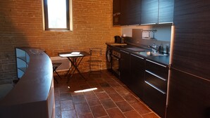 Cuina compacta amb paret de maó, una finestra i electrodomèstics moderns.