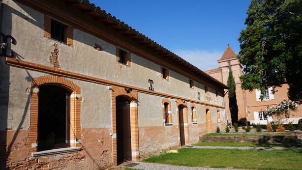 Un edifici històric amb portals arquejats i una torre.