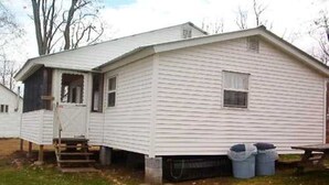 Une maison mobile de plain-pied avec un porche à l’avant et un petit garage attenant.