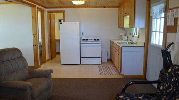 Eine kleine Küche mit Kühlschrank, Herd und Spüle, Holzschränken und einem Fenster mit Blick.