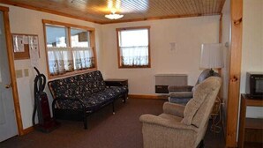 Ein gemütliches Wohnzimmer mit einer Couch, einem Sessel und einem Fernseher.