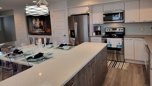 A modern kitchen with a large island, stainless steel appliances, and a fireplace. - Spacious 3 Room Condo Near Michigan's Piers and Waterways (Grand Haven)