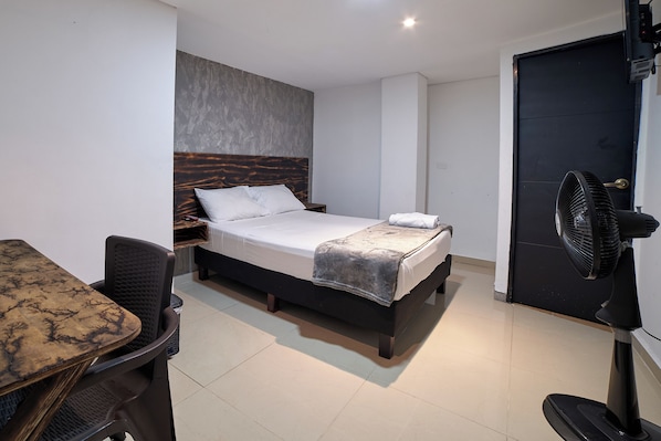 A modern hotel room with a bed, a desk, and a chair.