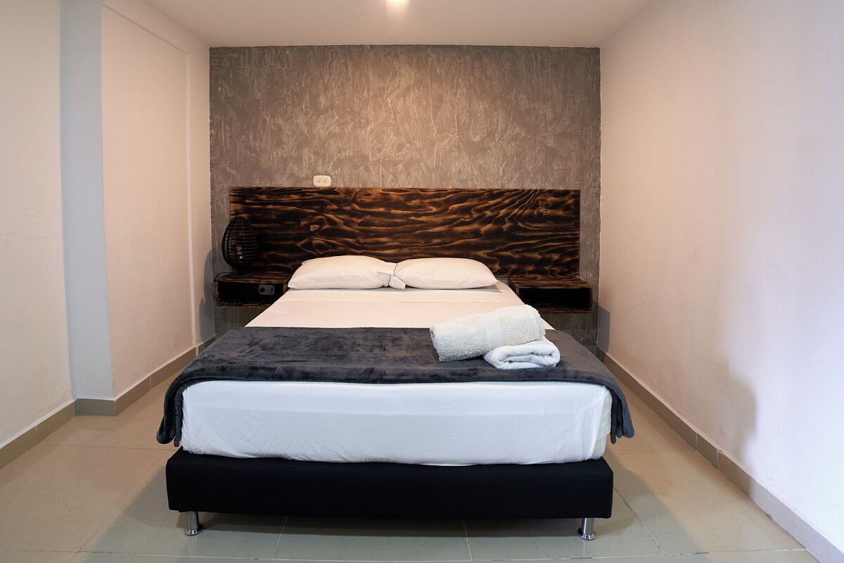 A neatly made bed with a dark headboard and white bedding.