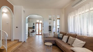 Ampla sala de estar com um sofá marrom, uma mesa de centro e escada que leva a um andar superior.