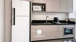 Eine moderne Küche mit Kühlschrank, Mikrowelle, Kaffeemaschine, Wasserkocher und Backofen.