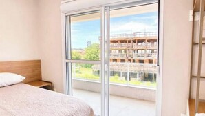 Ein Schlafzimmer mit großem Fenster, einem Bett und Blick auf ein im Bau befindliches Gebäude.