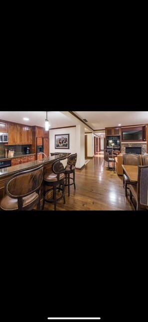 Enjoy a warm gathering space with a kitchen, bar, and seating area featuring a fireplace.