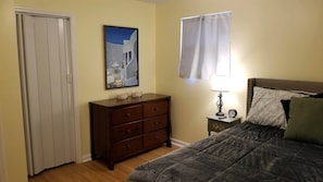 A bedroom with a bed, a dresser, a nightstand with a lamp, a clock, and a painting on the wall. - Close to Fort Eisenhower & Augusta Golf Course (Hephzibah)
