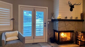 A cozy living room with a fireplace, a mounted deer head, and a sliding glass door. - Deer Valley Condo w/ Private Hot Tub (Park City)