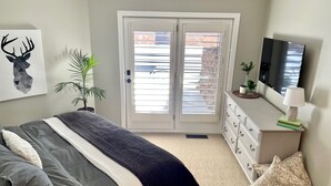 A bedroom with a bed, a dresser, a TV, and a window with blinds. - Deer Valley Condo w/ Private Hot Tub (Park City)