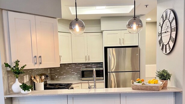 A modern kitchen with white cabinets, stainless steel appliances, and pendant lighting. - Deer Valley Condo w/ Private Hot Tub (Park City)