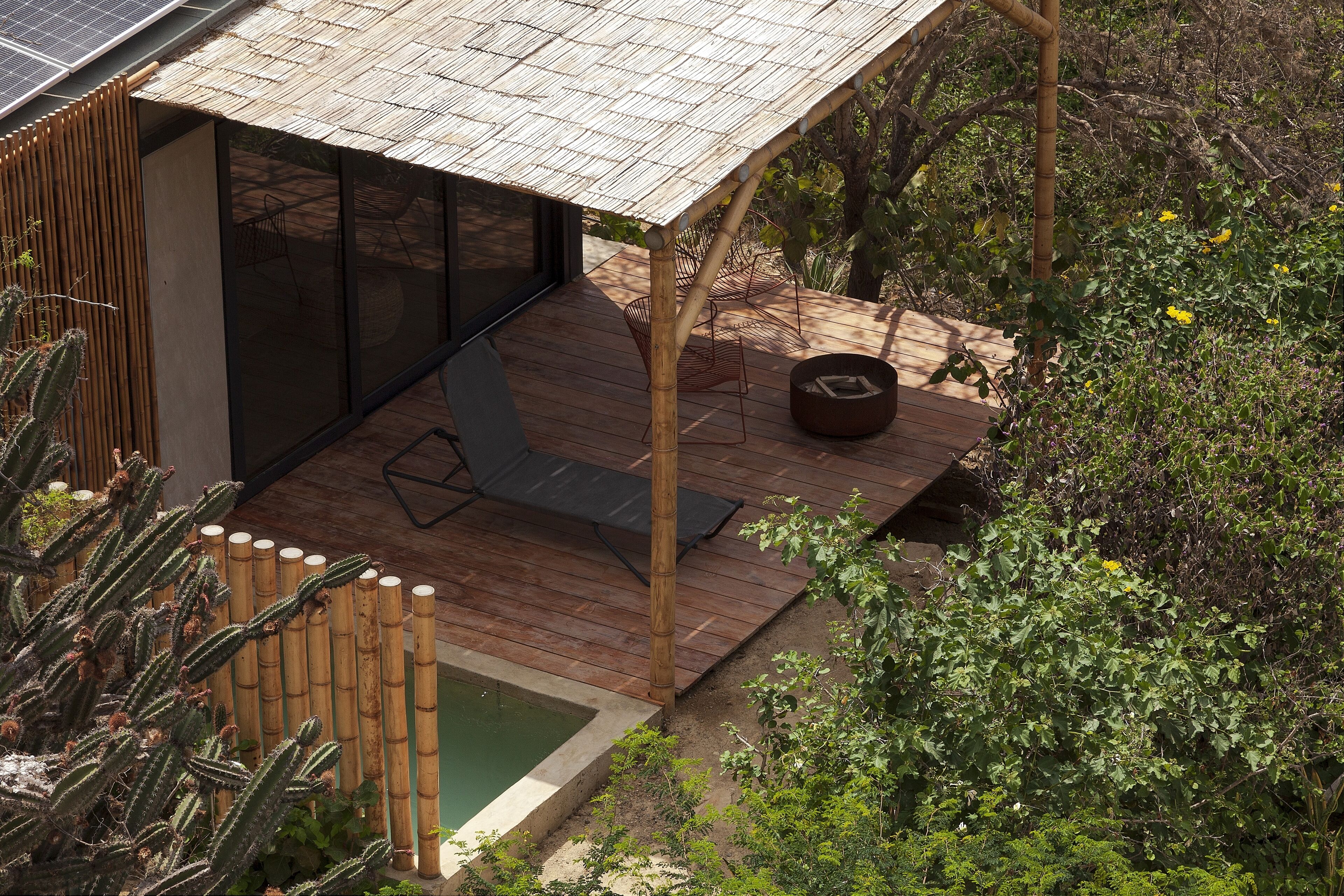 A modern outdoor deck with a pool, bamboo fence, and seating area.