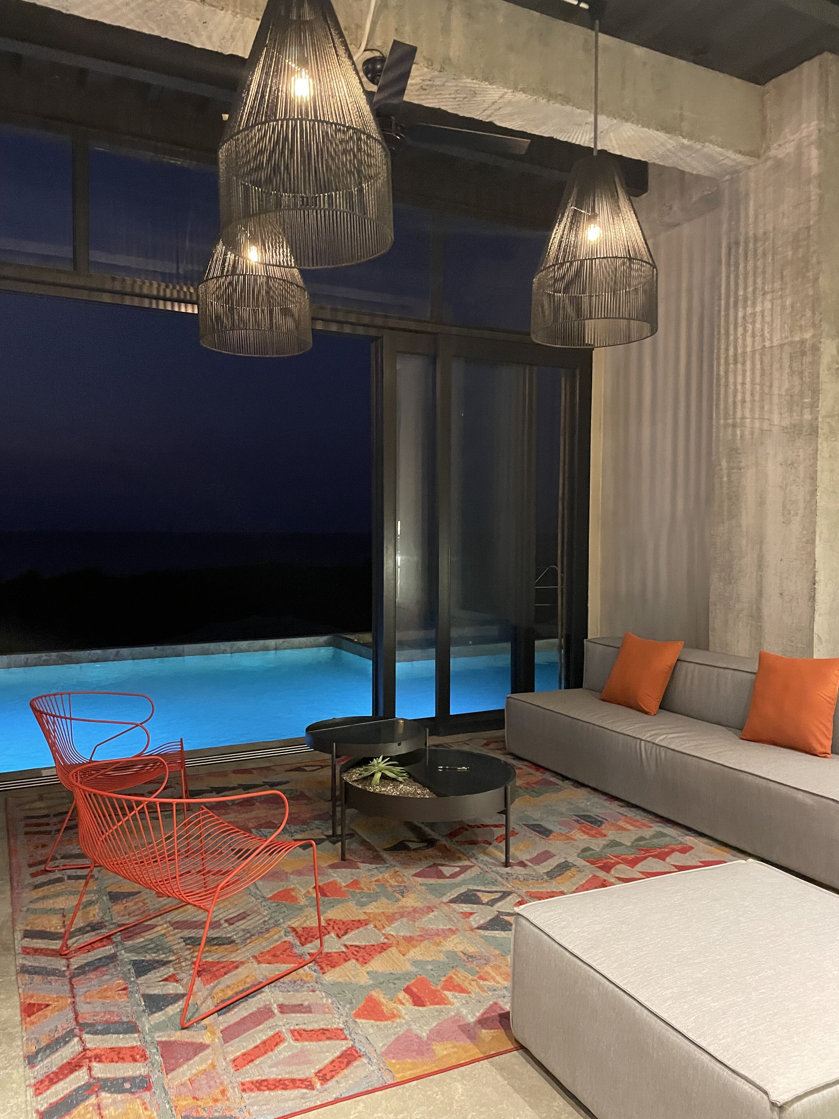Ein modernes Wohnzimmer mit Pool, einer Couch, einem roten Sessel und einem gemusterten Teppich.