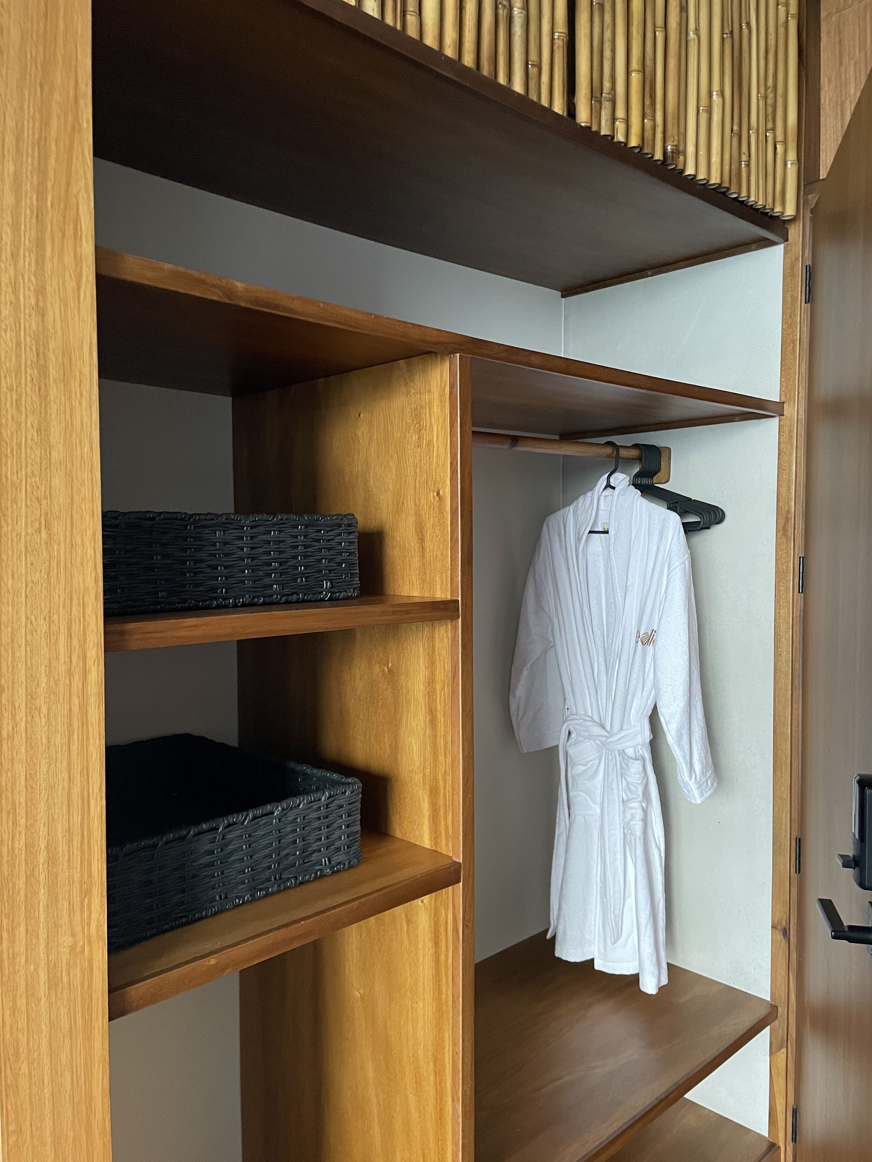 A wooden wardrobe with shelves and a hanging robe.
