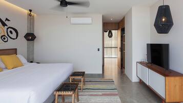 Habitació d'hotel moderna amb un llit gran, una televisió, un ventilador de sostre i vista al passadís.