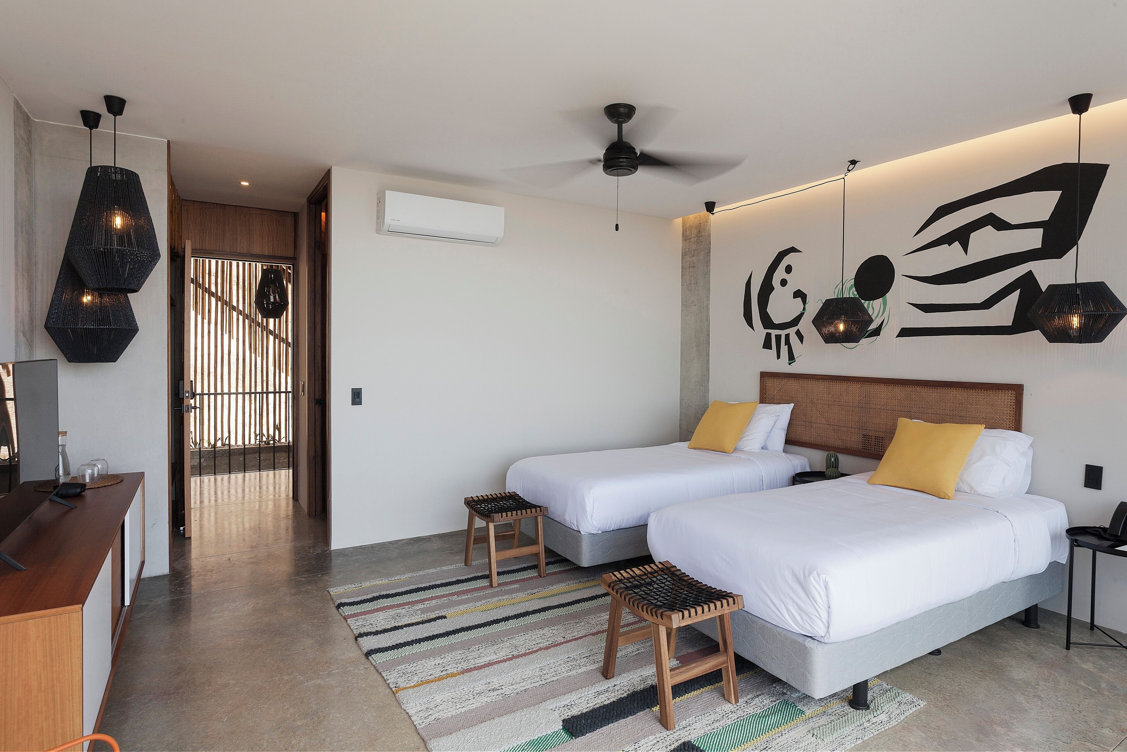 Une chambre d’hôtel moderne équipée de deux lits, d’un bureau et d’un ventilateur de plafond.