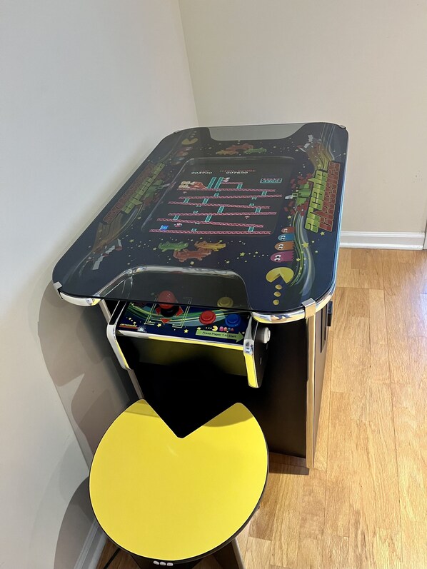 A table with a colorful design, a yellow chair, and a small cabinet underneath.