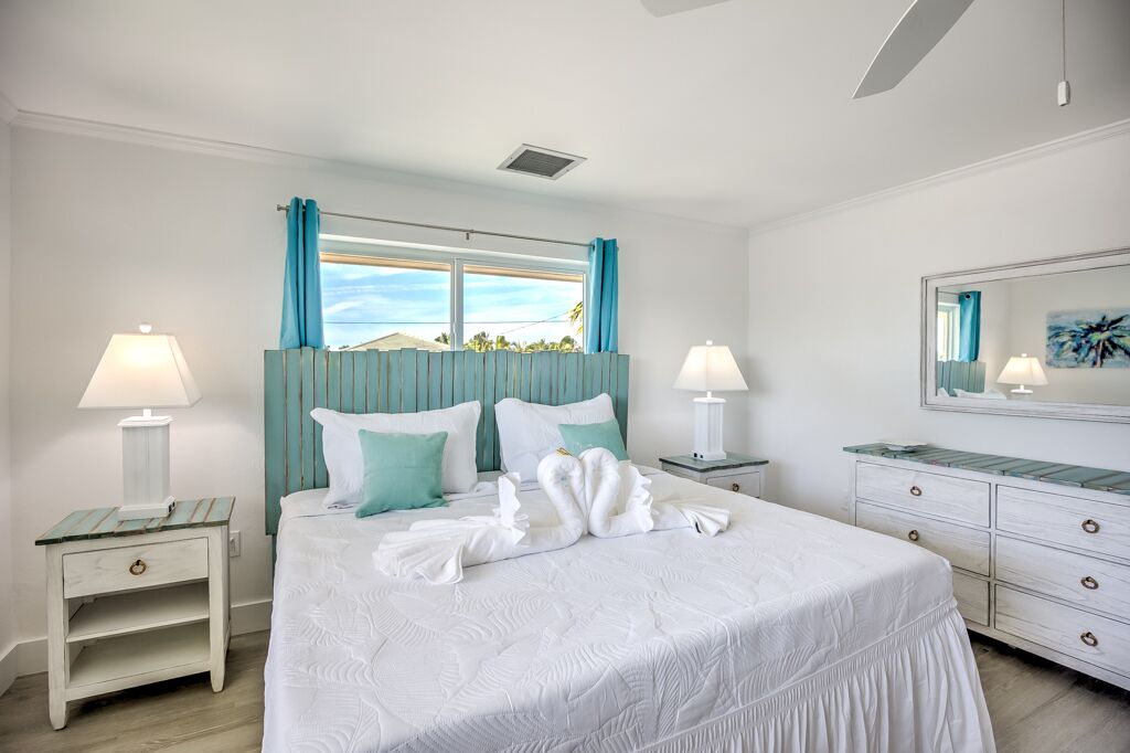 A neatly arranged hotel room with a large bed, two bedside tables with lamps, a dresser, and a large mirror.