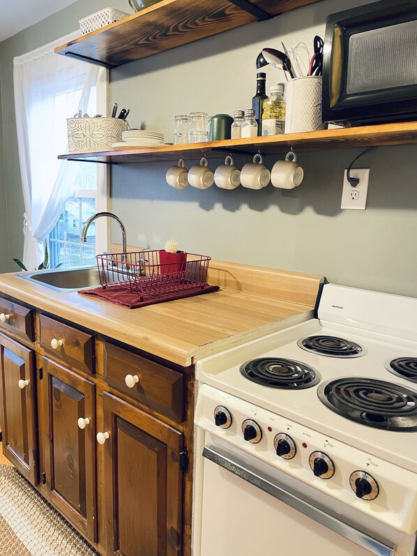 A kitchen with wooden cabinets, a white stove, and a window with a view.