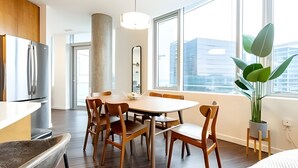A modern kitchen with a dining area, large windows, and a potted plant. - 2BR Penthouse | Gym | Bellevue | Sophari Towers E (Bellevue)