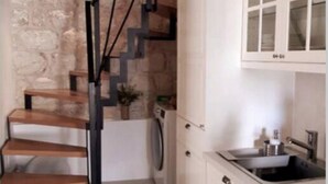 A kitchen with white cabinets, a stainless steel sink, and a wooden staircase. - Casa Ruben - Two Bedroom Holiday Home with Sea View (Vis)